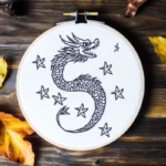 hand embroidery artwork of a dragon flying across the starry sky