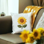 khaki sofa with a sunflower embroidered pillow and fresh sunflowers nearby