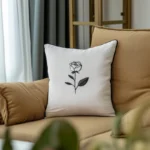khaki sofa with a white cushion embroidered with a black and white rose design