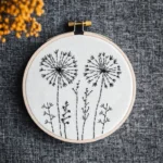 minimalist hand embroidery of a dandelion stitched with black thread