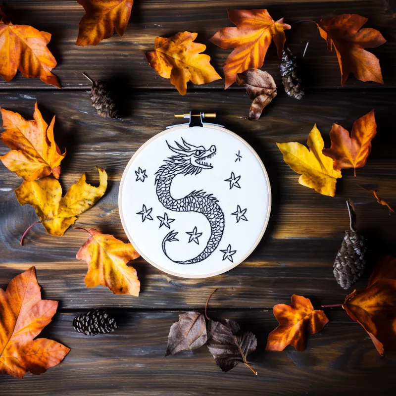 oriental dragon embroidery design on a wooden table with scattered autumn leaves oriental dragon embroidery design on a wooden table with scattered autumn leaves