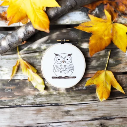 owl hand embroidery piece on the floor with trees and leaves as decoration
