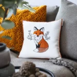 sofa with a fox embroidery cushion and an orange knitted pillow side by side