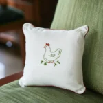white cushion on a green sofa featuring a freshly hand embroidered design