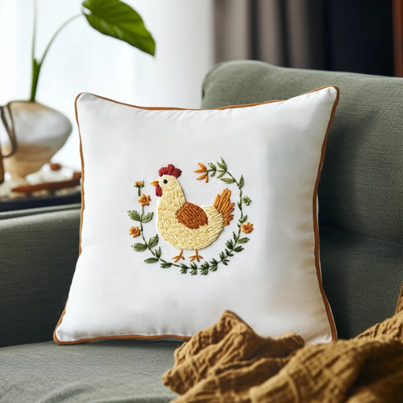 white cushion on gray sofa embroidered with a chicken and beautiful flowers white cushion on gray sofa embroidered with a chicken and beautiful flowers