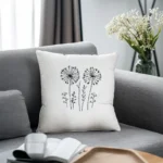 white cushion with dandelion embroidery placed on a gray sofa