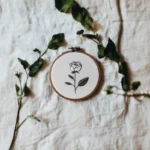 white fabric base with a rose embroidery piece and two branches