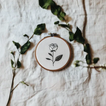 white fabric base with a rose embroidery piece and two branches