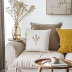 a cozy sofa with several pillows and a side table holding a cup and books