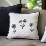 a deep blue pillow and a white embroidered pillow arranged on a khaki-colored sofa