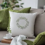 a green pillow and a white pillow embroidered with a green wreath placed on the sofa