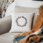 a pure white pillow embroidered with a floral wreath design