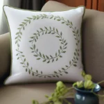 a white pillow embroidered with a double-layer green floral wreath