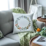 a white pillow embroidered with a wildflower wreath, paired with a green embroidered blanket