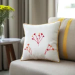 a white pillow embroidered with three red flowers