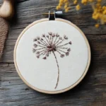 dandelion embroidery displayed in a hoop on a table