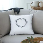gray and white cushions on the sofa, with a basket holding a cup next to them