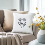 light khaki sofa with two pillows and a vase of fresh flowers beside it