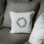 small white pillow with a floral wreath embroidery placed on a gray sofa
