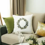 three decorative pillows on the sofa with a bouquet of fresh flowers in front