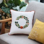 two embroidered pillows on the sofa with a green houseplant beside them