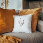 two orange pillows and a white embroidered pillow arranged on the sofa