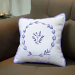 white cushion embroidered with a purple floral wreath and a small bouquet in the center