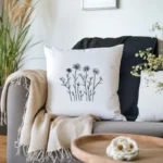 white cushion on the sofa embroidered with a black line-art wildflower design