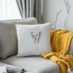 white decorative pillow and a yellow throw blanket placed on a sofa