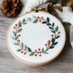 winter-inspired wreath embroidery with green leaves and red berries