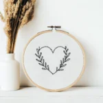 close-up of a minimalist black line leaf heart embroidery pattern inside a wooden hoop