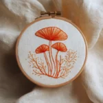 close-up of orange line art mushroom motif in an embroidery hoop