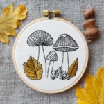 hand-stitched mushroom and autumn leaf motif in a hoop