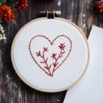 minimalist red branch heart embroidery in a hoop next to blank paper