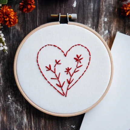 minimalist red branch heart embroidery in a hoop next to blank paper