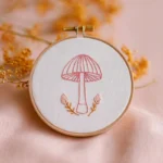 pink mushroom hand embroidery pattern in a wooden hoop on soft pink fabric