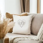white decorative cushion featuring a dashed heart and simple botanical needlework resting on a beige couch