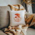 white throw pillow featuring orange stitched mushrooms on a sofa